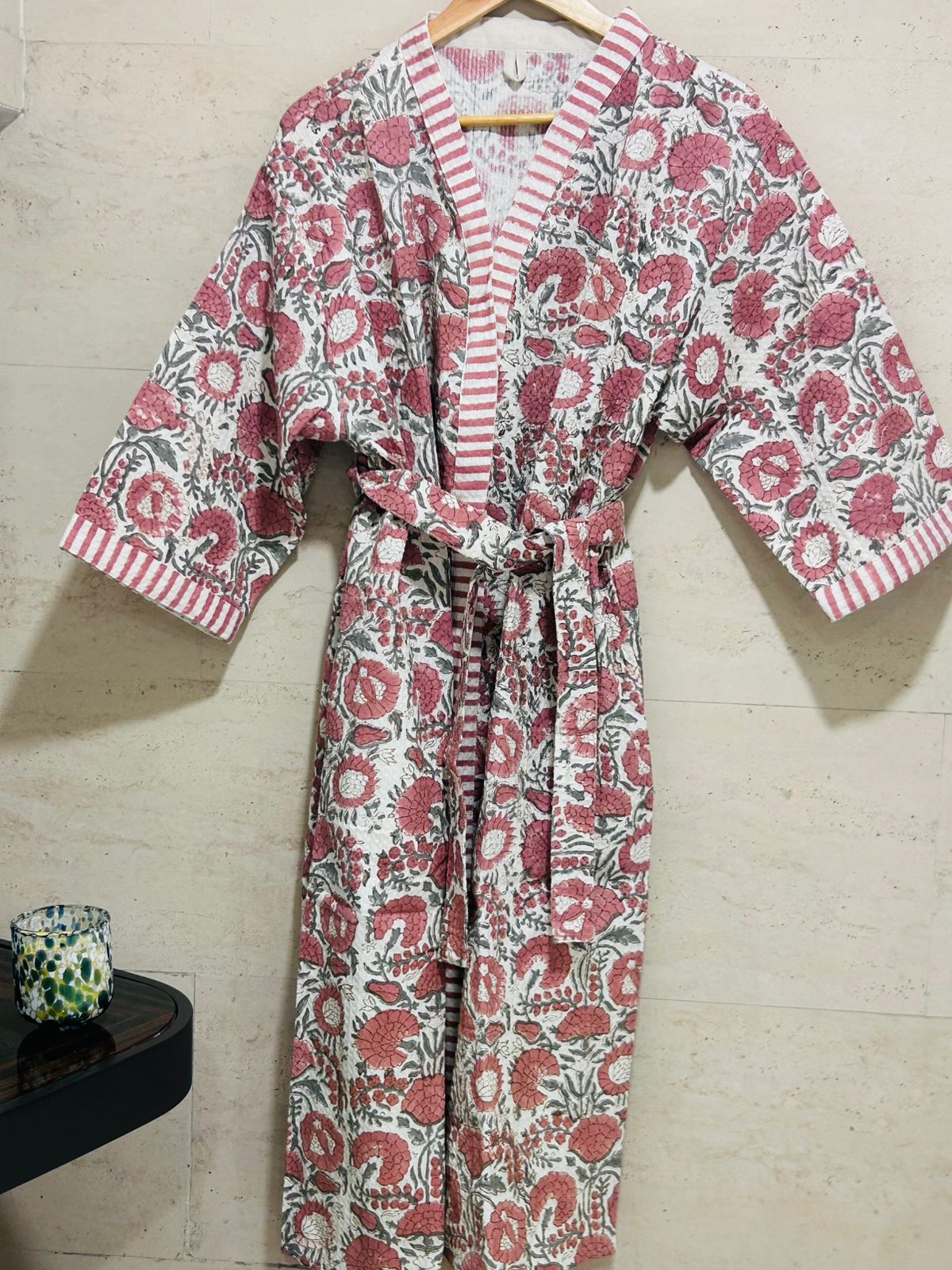 Floral patterned robe on a hanger against a tiled wall.