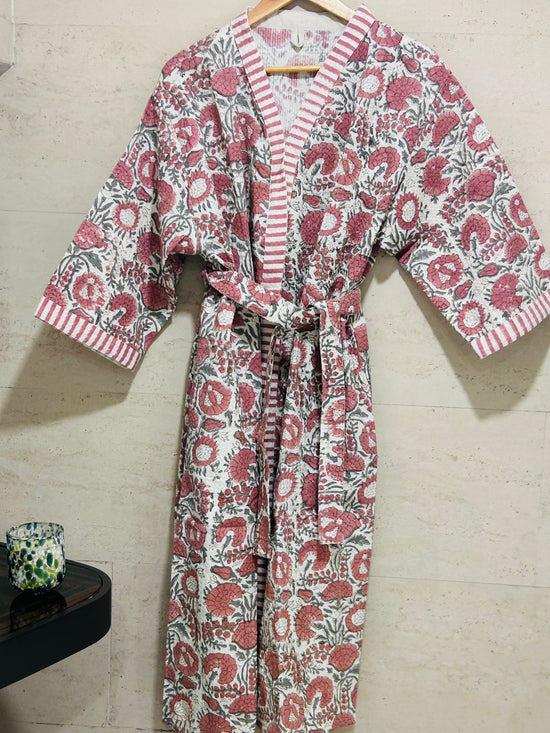 Floral patterned robe on a hanger against a tiled wall.